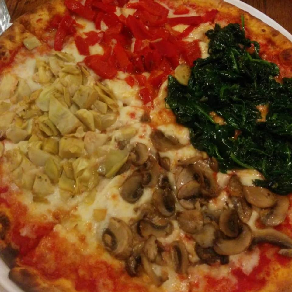 PIZZA STAGIONE A pizza divided into quarters and topped individually with mushrooms, artichokes, spinach, and roasted peppers