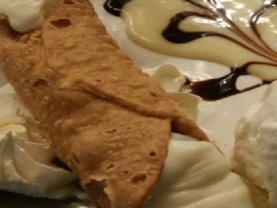Cannoli, ice cream, whipped cream served on a white plate.