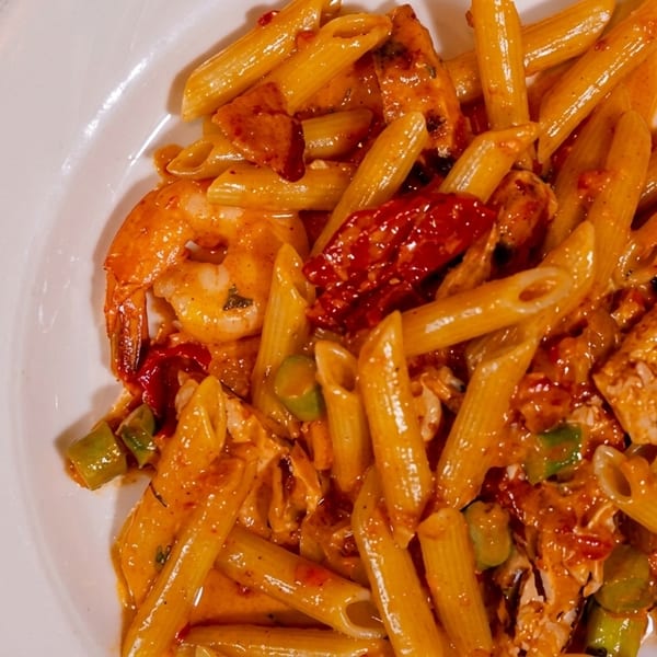 Penne pasta with shrimp, chicken, sun-dried tomatoes, and green beans in a creamy orange sauce.