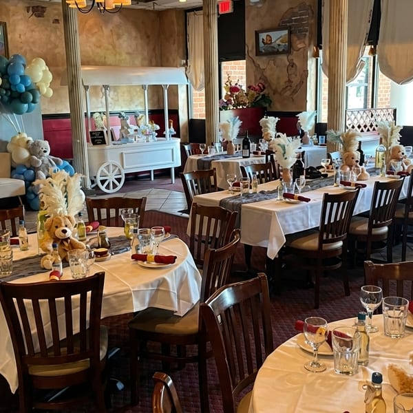 Restaurant dining room decorated for a baby shower with teddy bears, balloons, and set tables.