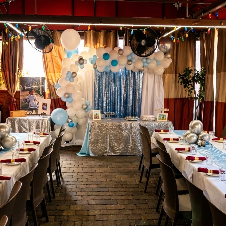 A restaurant dining room set up for a party with long tables, balloons, and a dessert station.