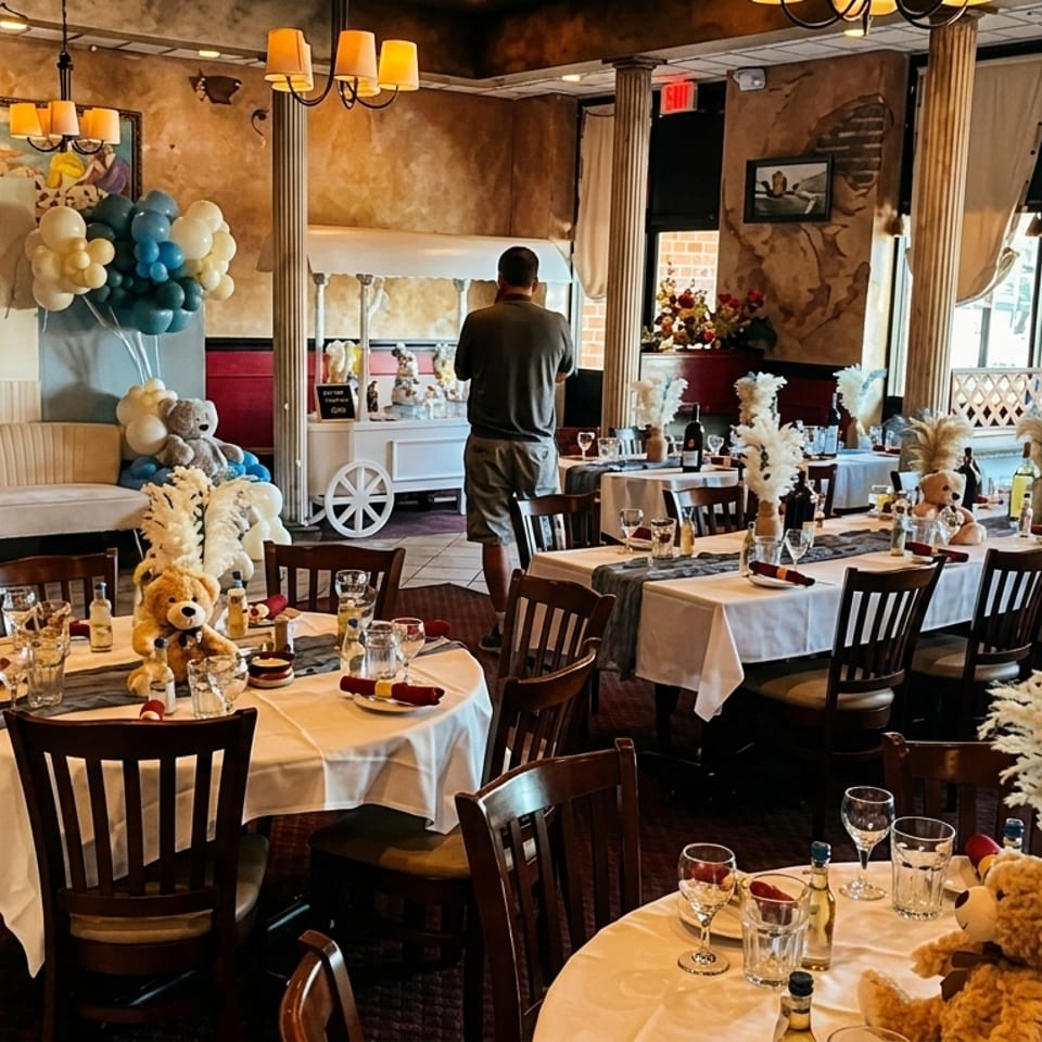 Restaurant dining room set for a baby shower with blue and white balloons, teddy bears, and decorated tables.